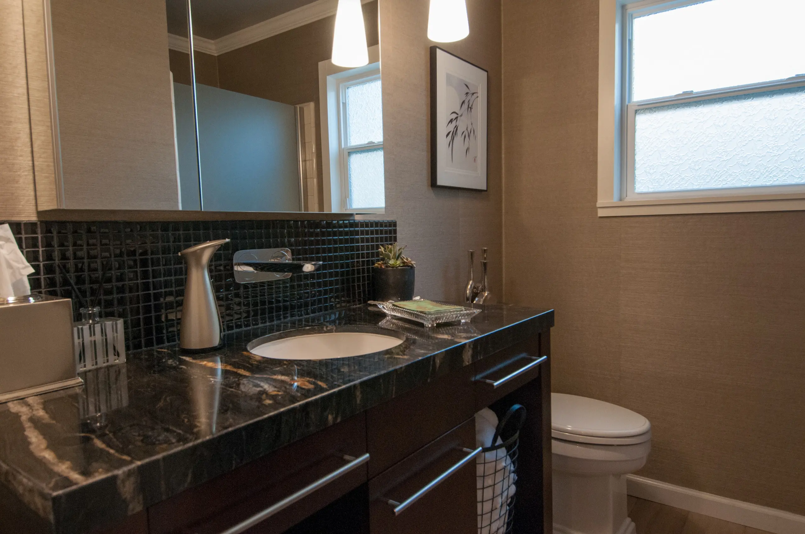 Modern bath vanity with black granite counter and glass mosaic backsplash in Brea