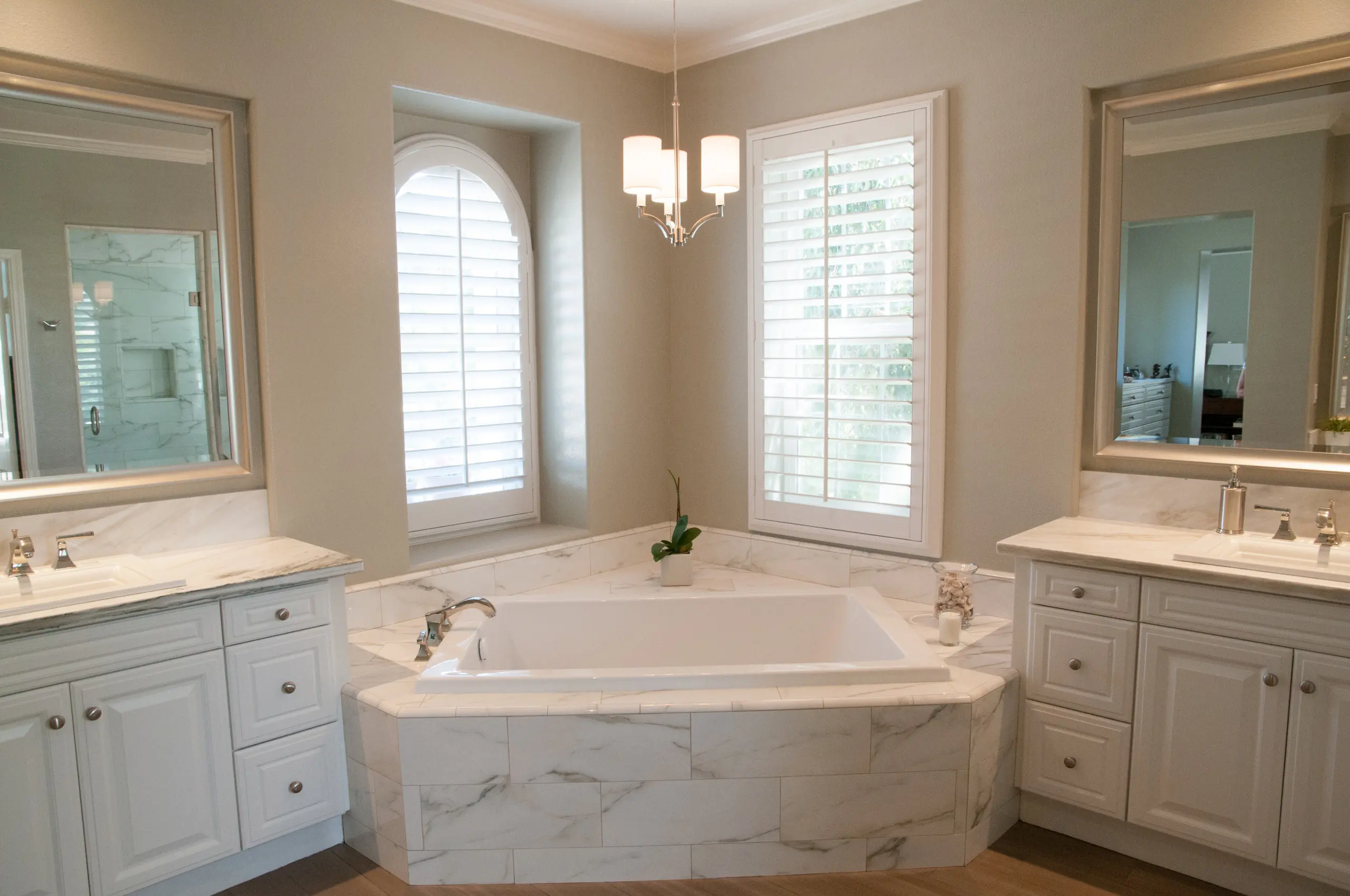 Marble and white master bath with dual vanities and corner soaking tub in Irvine